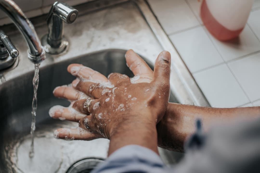 Hands being washed with soap at a sink