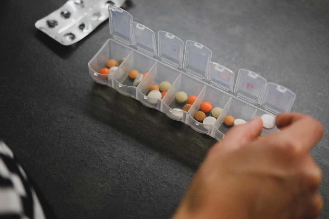 A hand taking a tablet from a weekly pill organiser