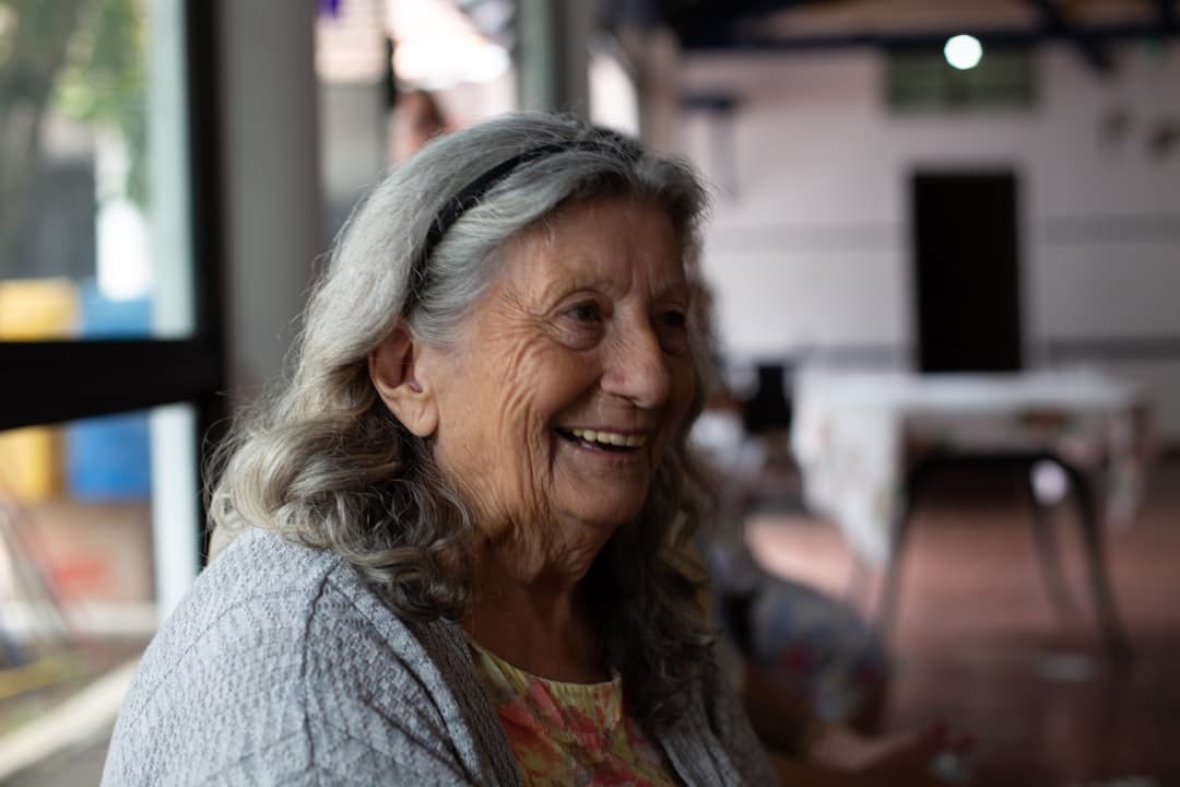 An older woman smiling as she listens